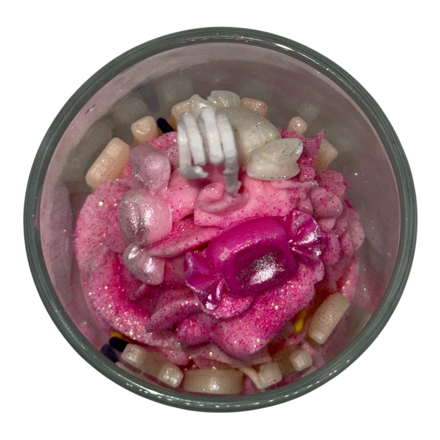 Top view of a Luxe Name Glow Collection personalized whipped scented candle with pink glittery swirls, custom wax letters, and candy-shaped decorations in a glass jar