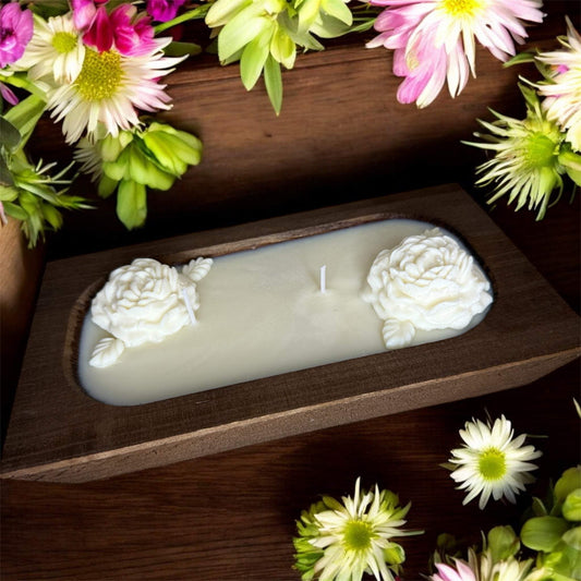 12 oz handcrafted luxury candle in a wooden bowl with rose embellishments, surrounded by colorful flowers.