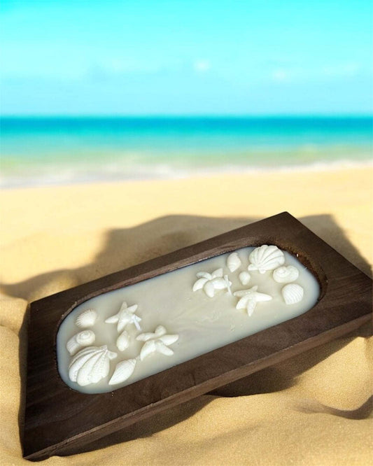 Ocean Bliss Luxe Candle in wooden bowl with shell and starfish accents on beach.