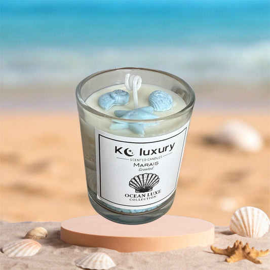 SeaGlass Glow candle from OceanLuxe Collection by KC Luxury, featuring ocean-inspired design against a beach backdrop.